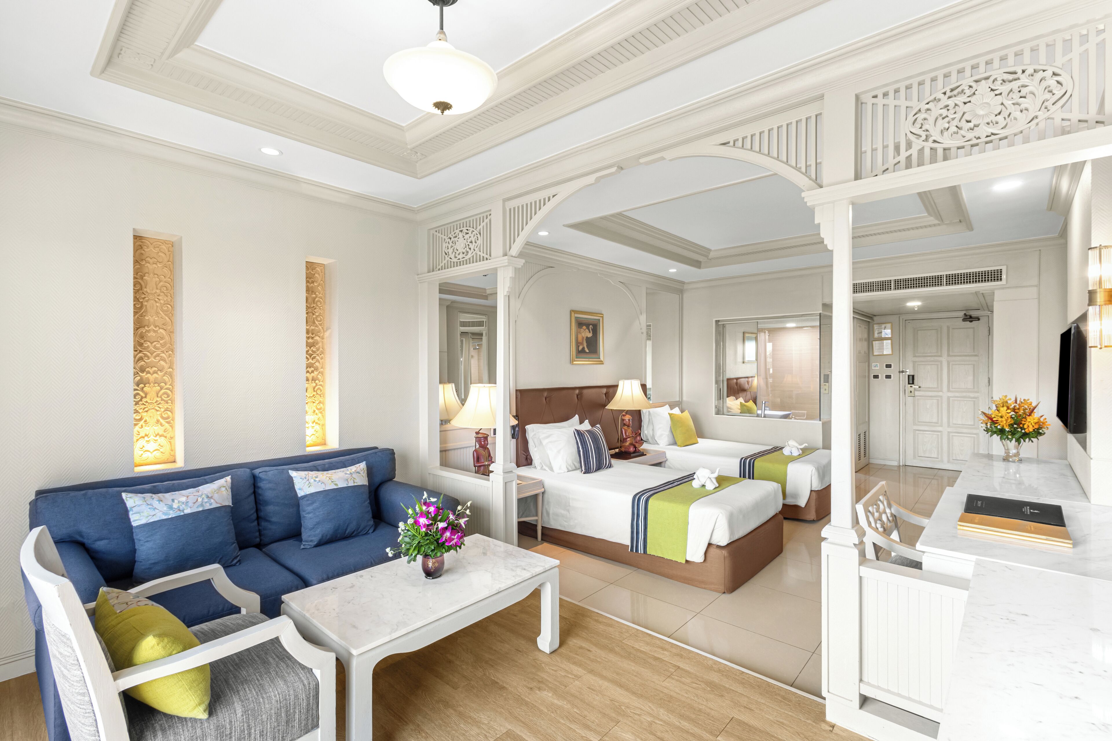 A hotel room with a sofa, a bed, a desk, and a bathroom visible through an open door.