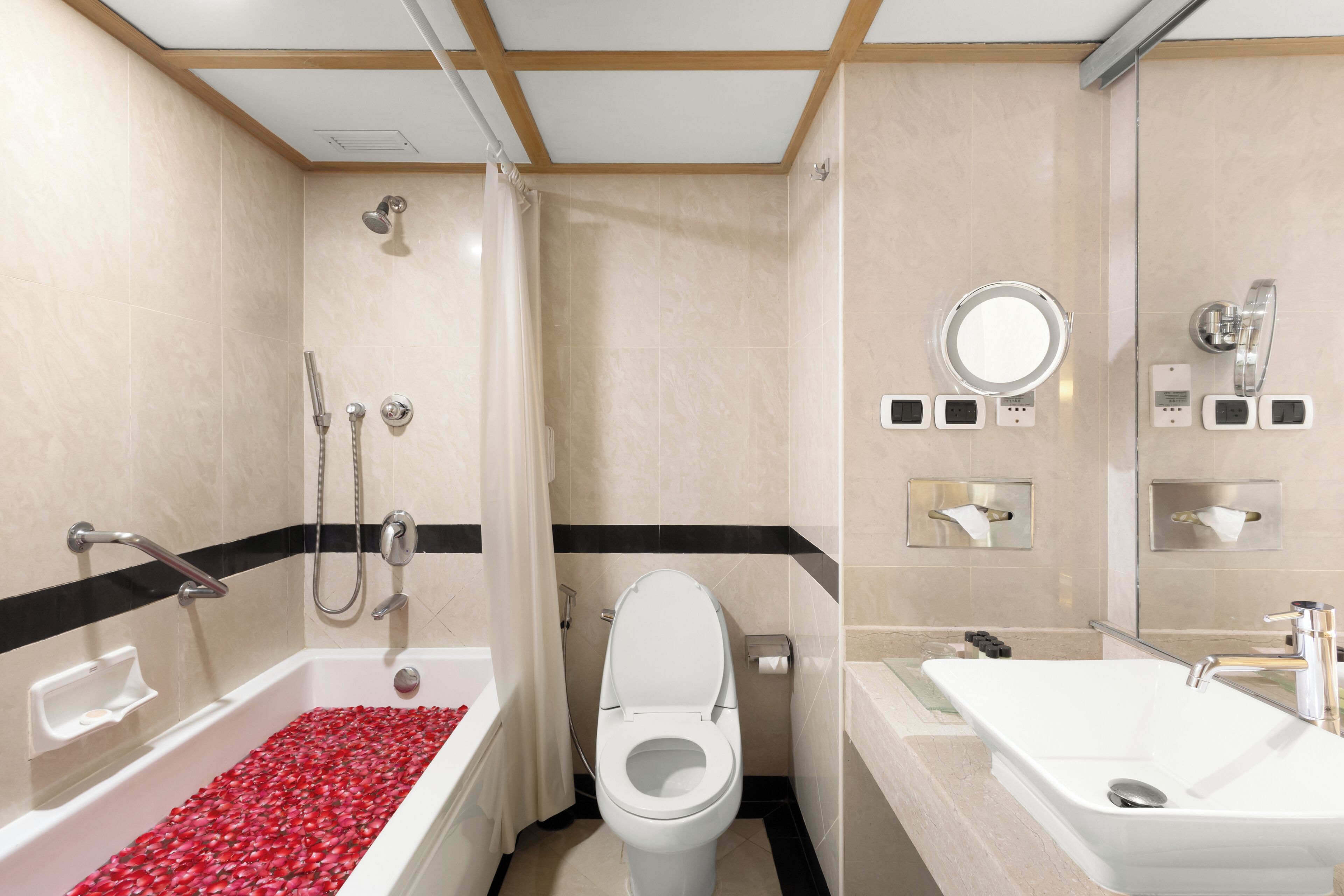Baño con bañera, inodoro y lavabo, que incluye ducha, dispensador de toallas y un espejo.