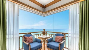 Un balcón con dos sillones azules, una mesita y vista al océano.