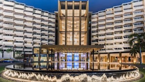 Un hotel con un atrio central, varios balcones y una fuente acuática reflectante al frente.