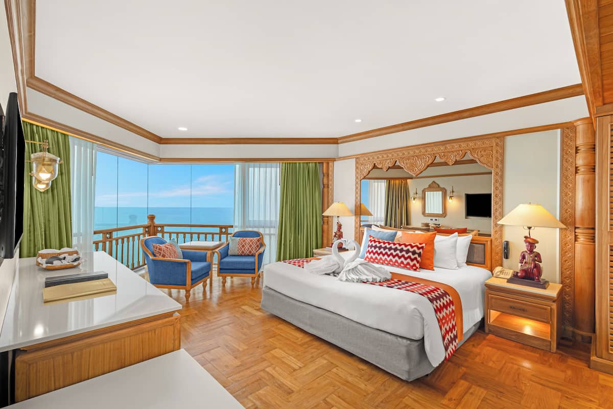 Ett rymligt hotellrum med en stor säng, ett skrivbord, en stol och en balkong med utsikt över havet.