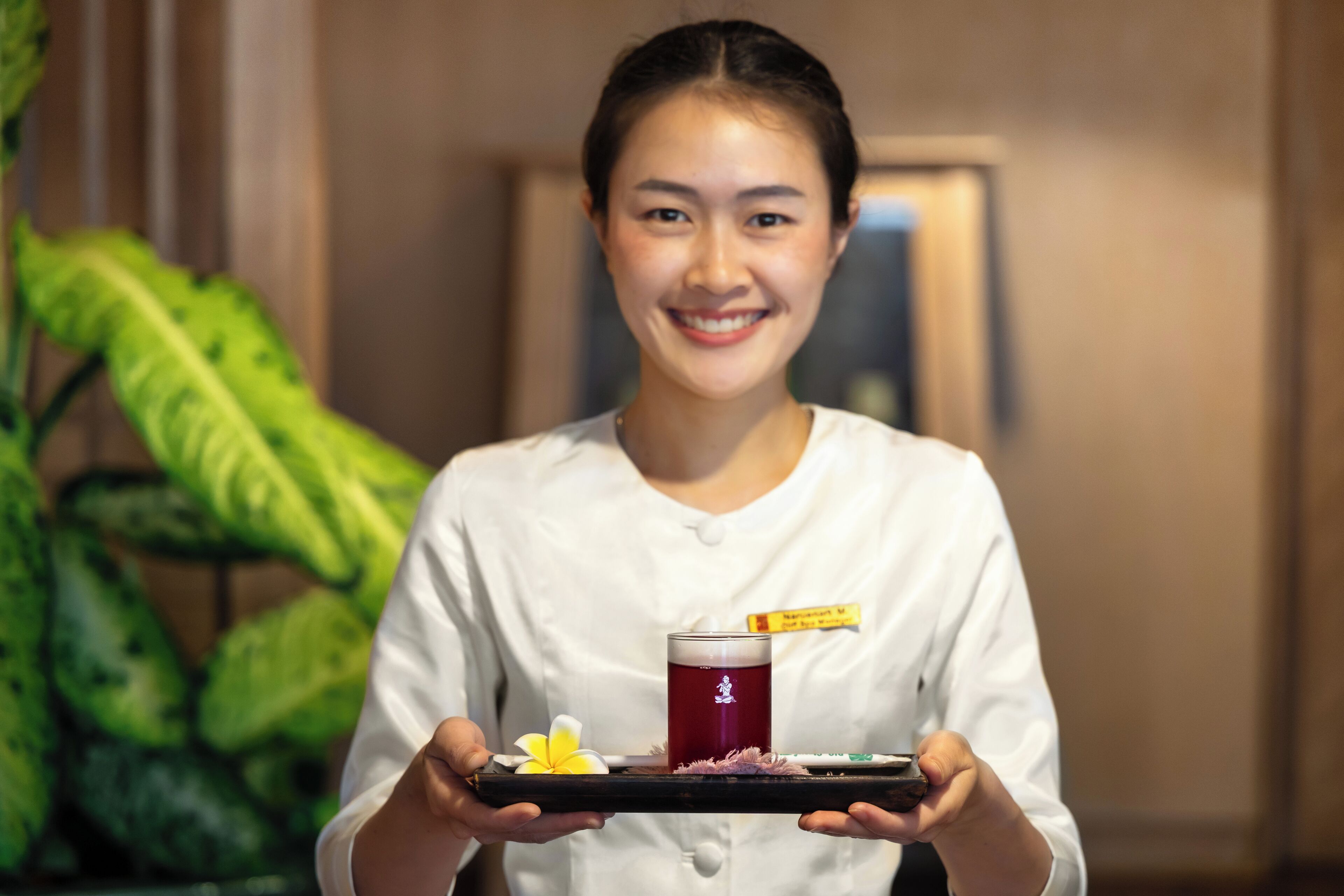 A person holding a tray with a drink and a flower.