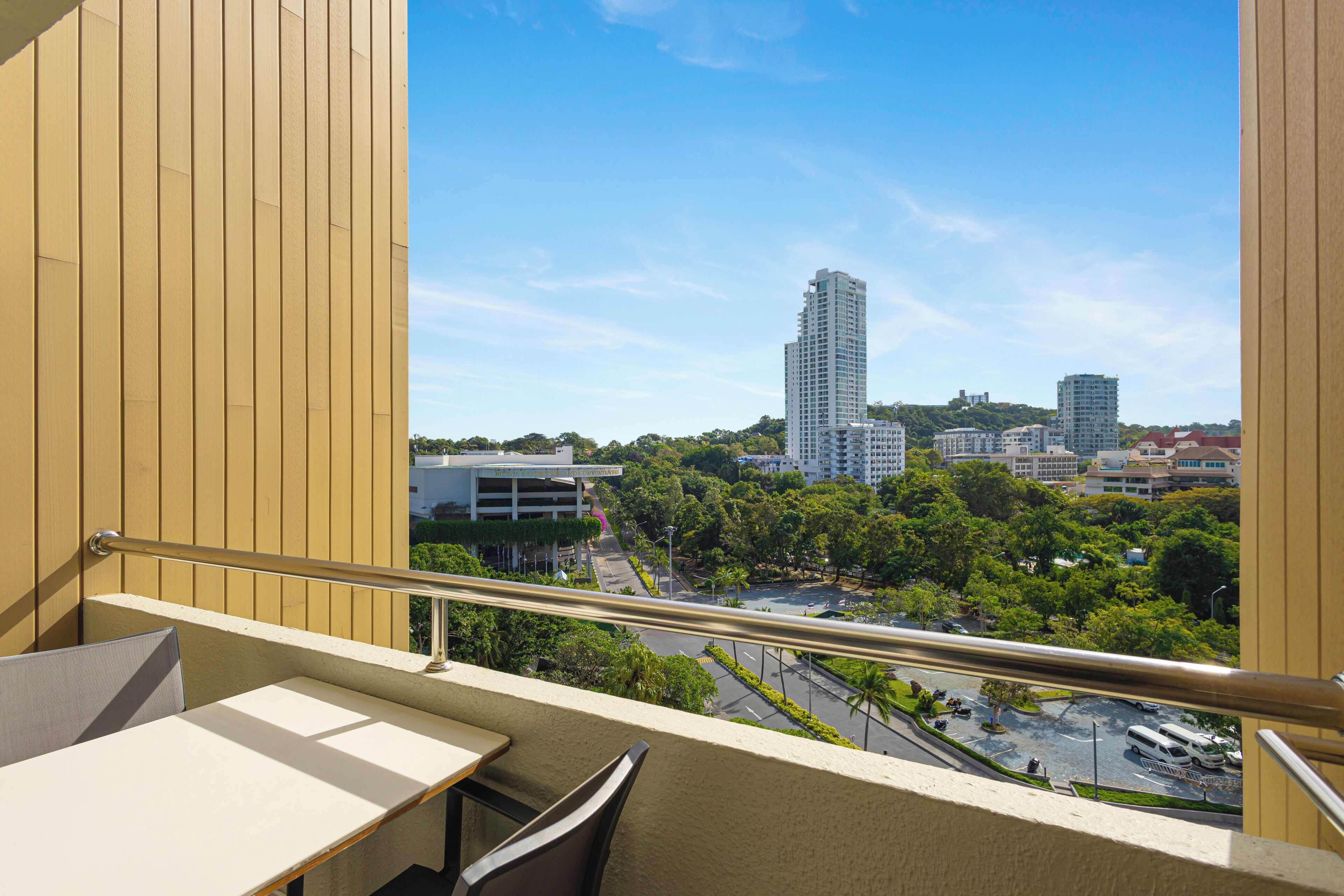 A balcony with a view of a cityscape, including tall buildings and a parking area.