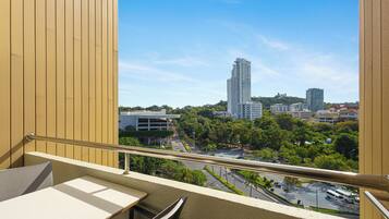 A balcony with a view of a cityscape, including tall buildings and a parking area.
