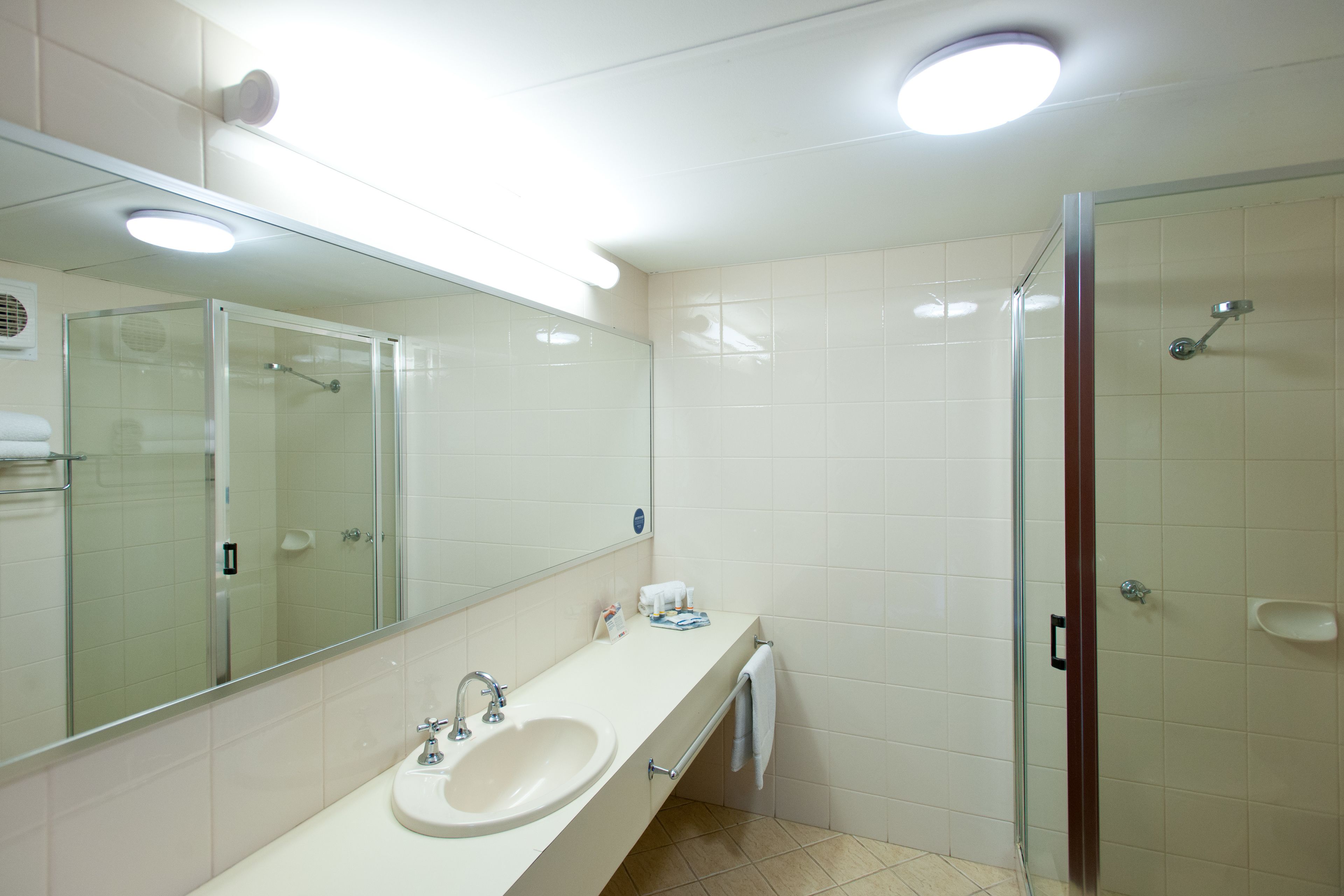 Een moderne badkamer met een wastafel, spiegel en douchecabine.