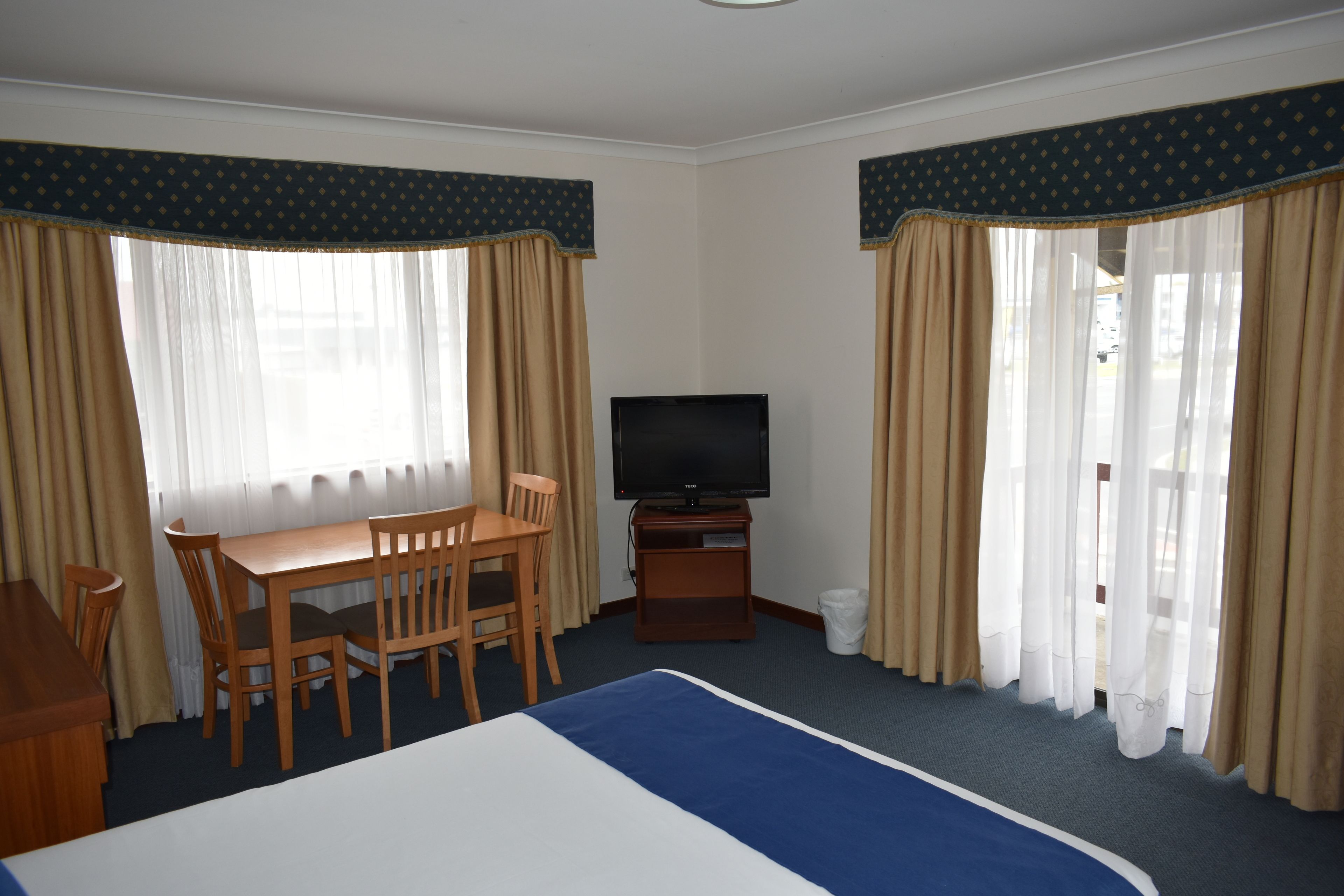 A hotel room with a bed, a TV, a desk, and two chairs.
