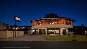 Um hotel moderno com estrutura em dois andares, área de estar coberta ao ar livre e uma placa com o nome 'ADIRAL'.