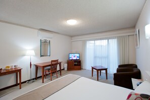 A hotel room with a bed, a desk, a chair, a television, and a window with curtains. - Admiral Motel Bunbury (Bunbury)