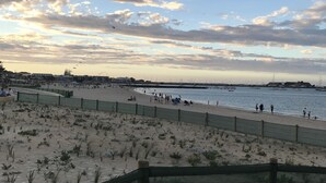 Uma praia com areal, uma cerca e vista para o mar.