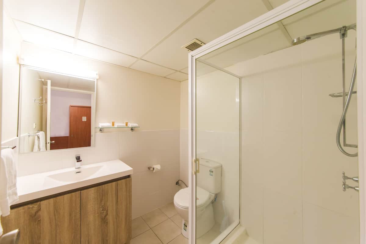 A bathroom with a wooden vanity, a glass shower enclosure, and a toilet.