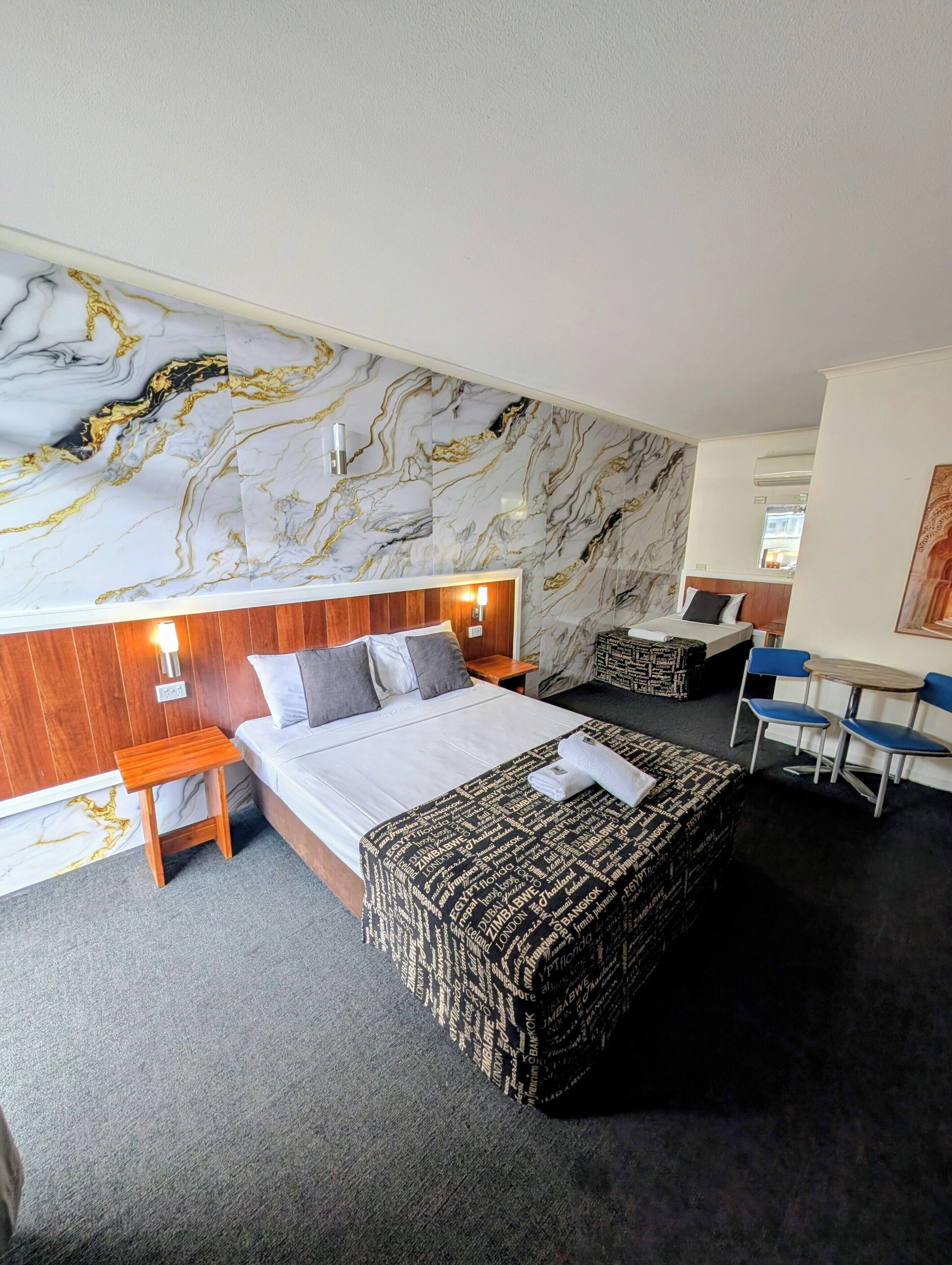 Une chambre d’hôtel comprenant un lit, une table de chevet et un coin salon avec une table et des chaises.