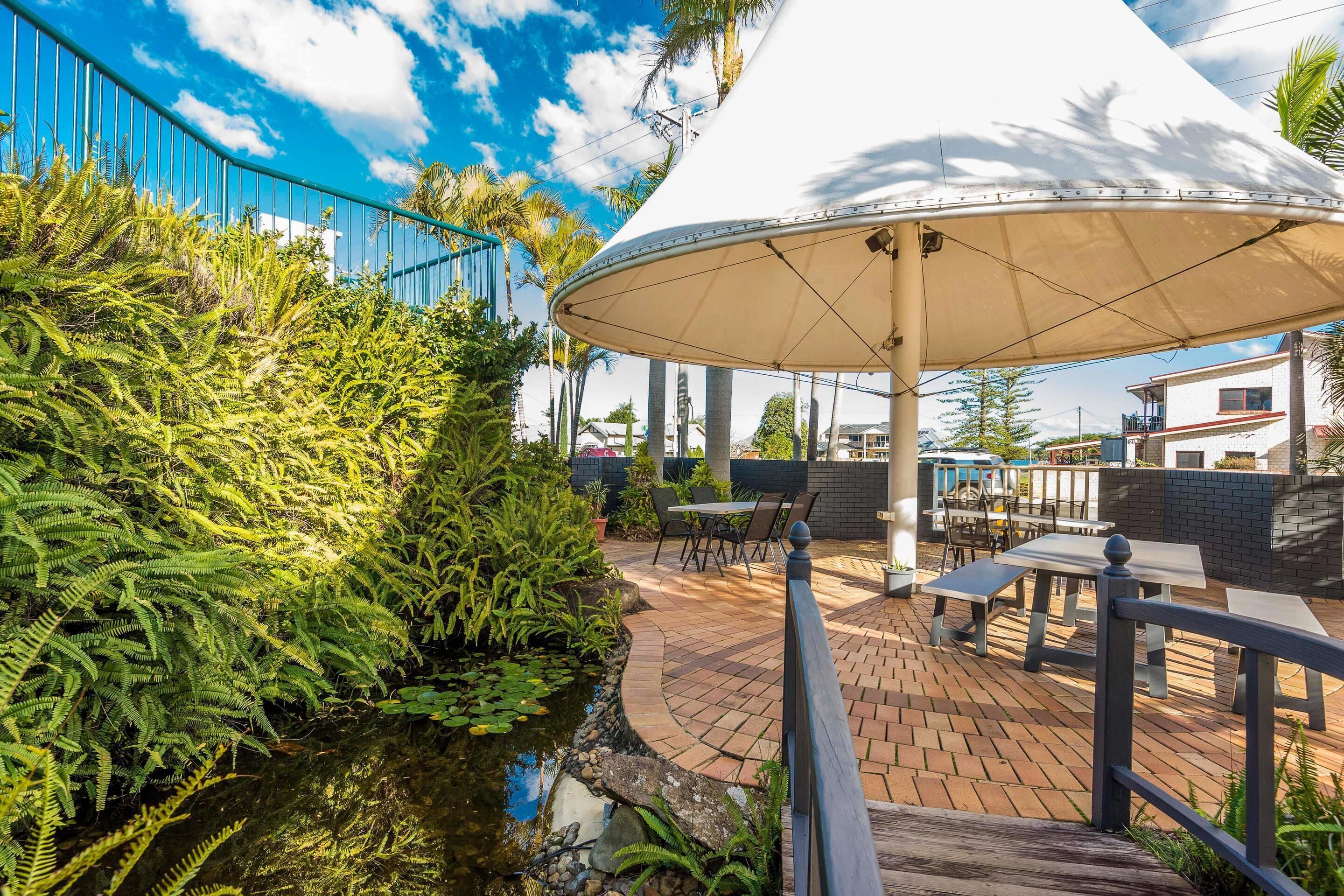 An outdoor patio area with a water feature, seating, and a large umbrella.