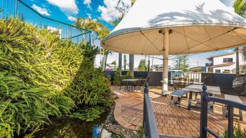 An outdoor patio area with a water feature, seating, and a large umbrella.