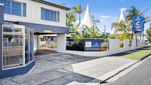 A hotel entrance with a modern design, featuring a glass facade and a sign indicating 'Comfort Inn' and 'Seasonz Inn' availability.