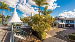 A hotel with a parking lot, a white conical structure, and palm trees.