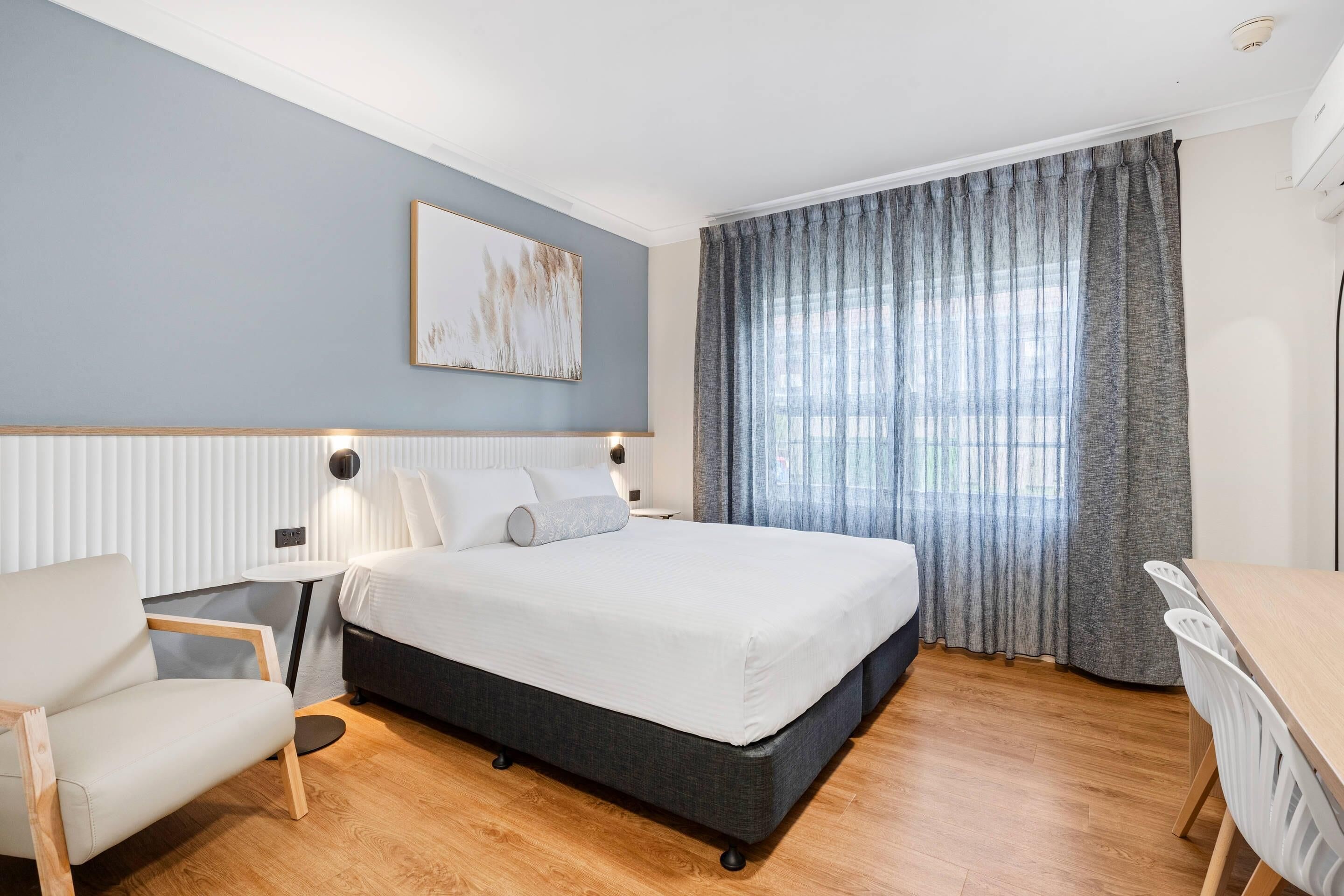 Ein modernes Schlafzimmer mit einem großen Bett, einem Nachttisch, einem Sessel und einem Schreibtisch.