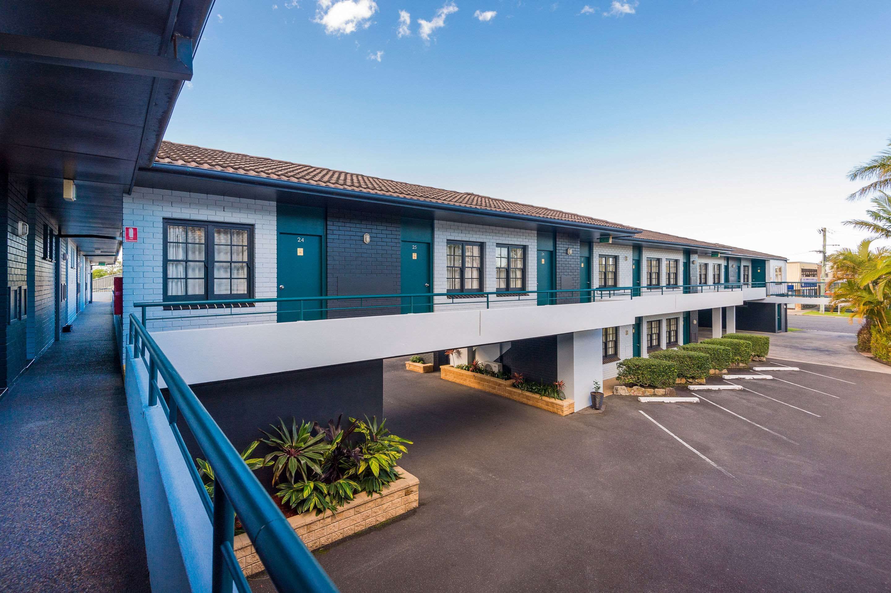 Un motel con pasillo cubierto, habitaciones individuales y zona de estacionamiento.