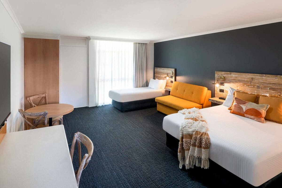 A hotel room with a bed, a sofa, a desk, and a chair.