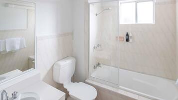 A modern bathroom with a toilet, sink, and glass-enclosed shower.