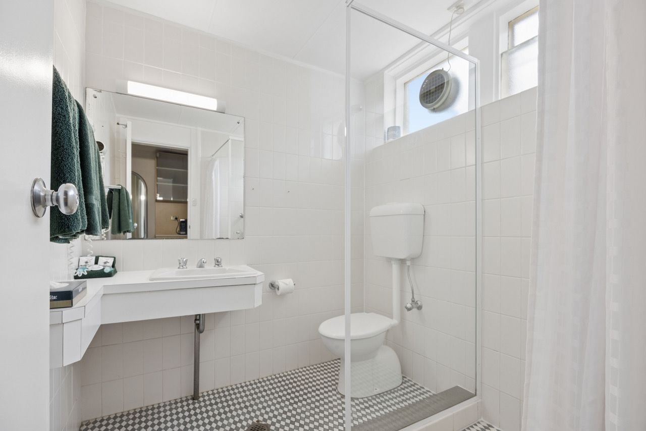 A bathroom with a white sink, mirror, and toilet.