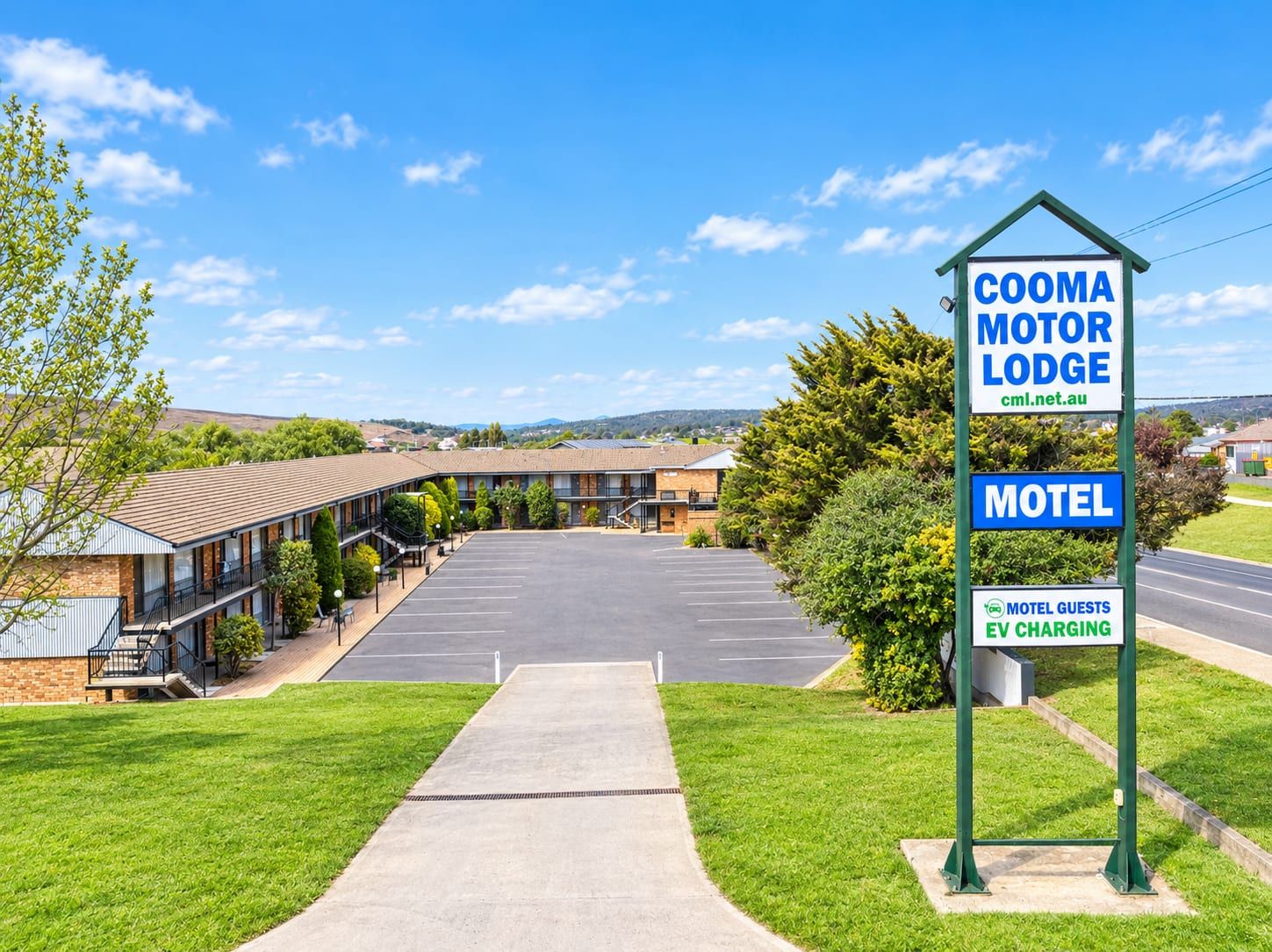 Un motel con un cartello che indica Cooma Motor Lodge e colonnine di ricarica per veicoli elettrici a disposizione degli ospiti.