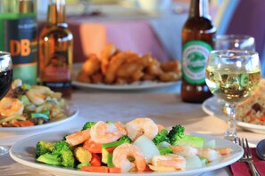 Une table à manger avec des assiettes remplies de nourriture, des verres à vin et des bouteilles.