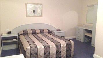 A bedroom with a bed, a nightstand, a dresser, a mirror, and a wall-mounted picture.