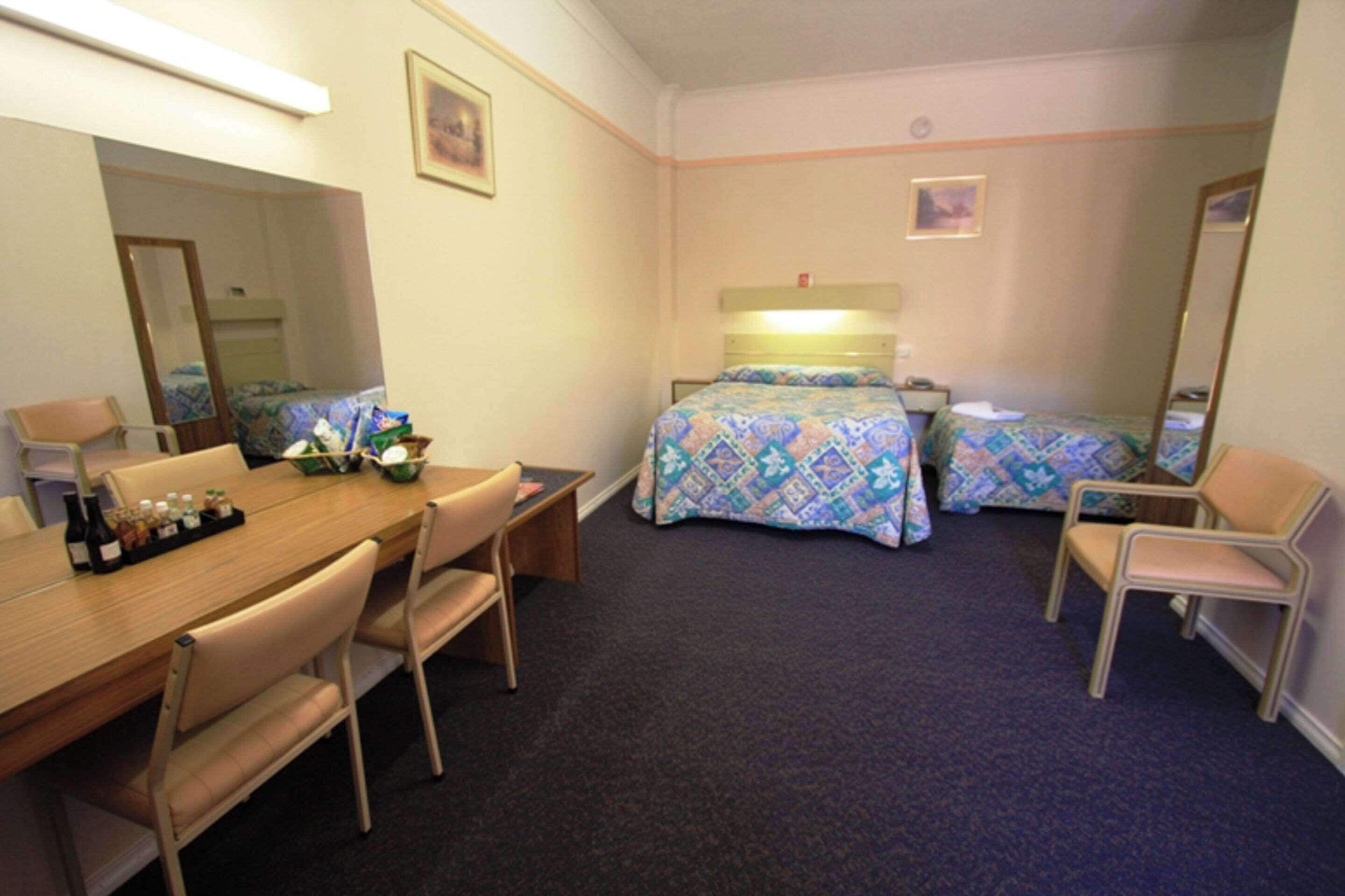 A hotel room with a bed, a desk, a chair, and a mirror.