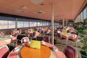 A dining area with tables and chairs, a menu stand, and large windows offering a view. - Comfort Inn Crystal (Broken Hill)