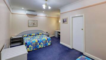A bedroom with a bed, a desk, a chair, and a wardrobe.
