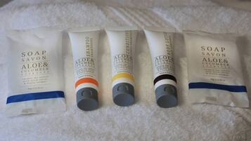 Four tubes of shampoo and soap on a white towel.