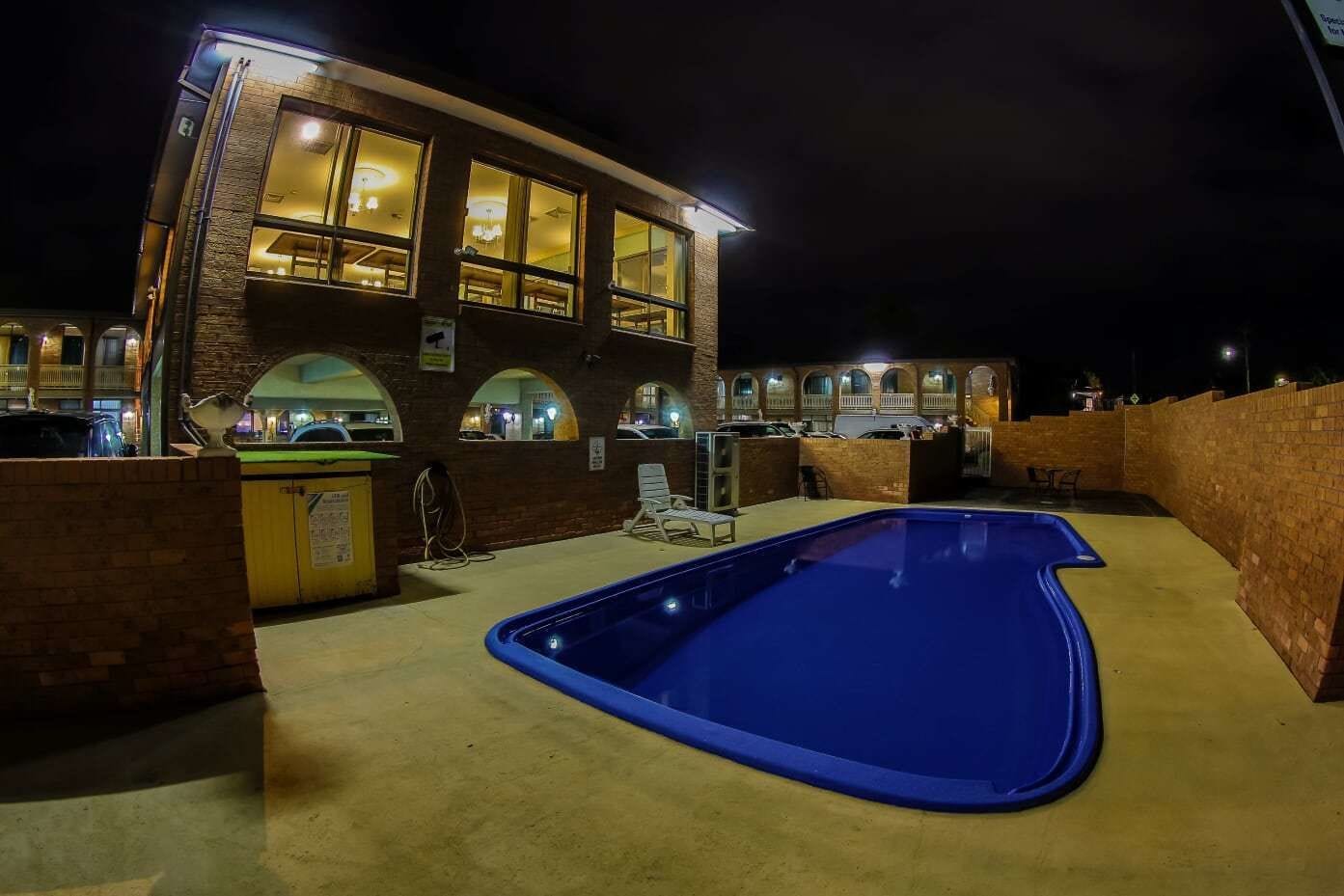 Hotel amb piscina, zona de seients a l'exterior i façana de maó.