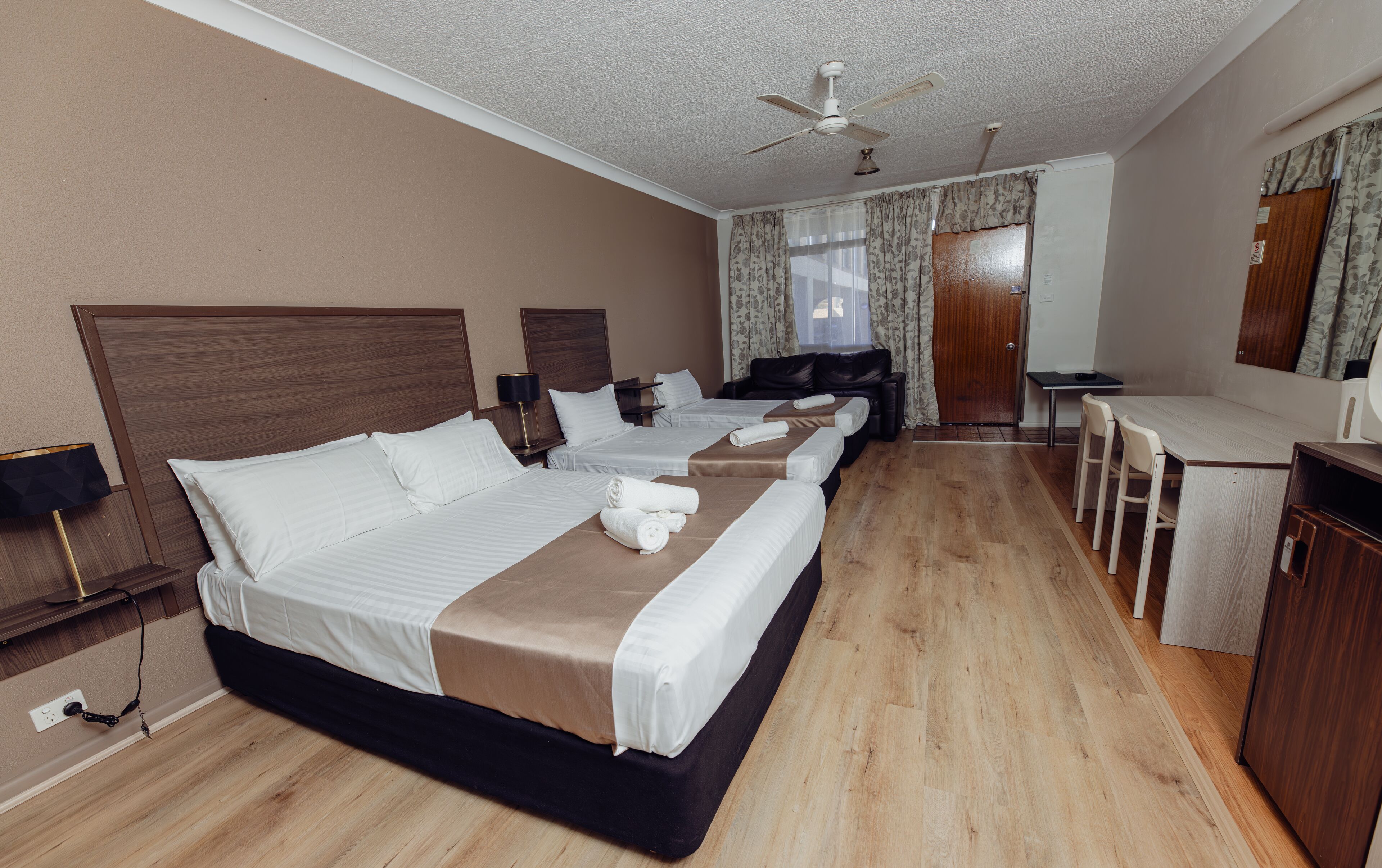 A hotel room with a large bed, a desk, and a chair.