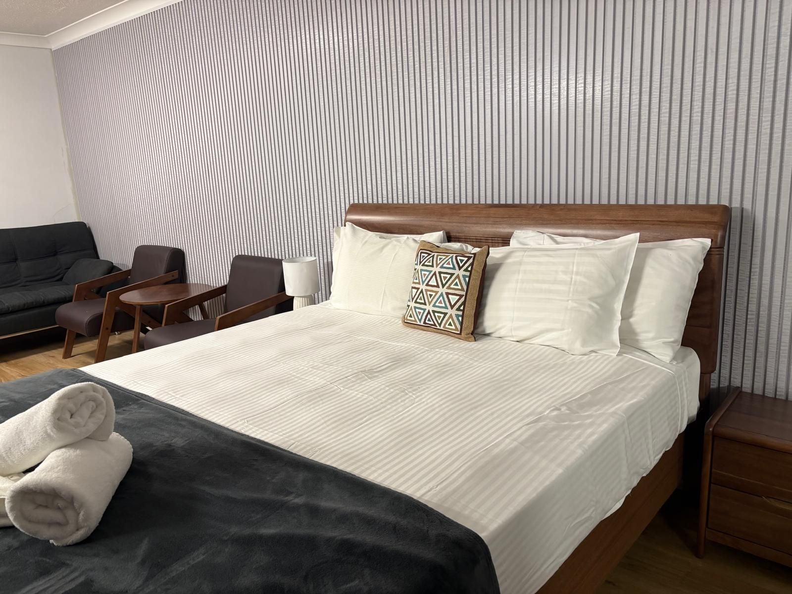 Una habitación de hotel con cama, escritorio, silla, sofá y lámpara.