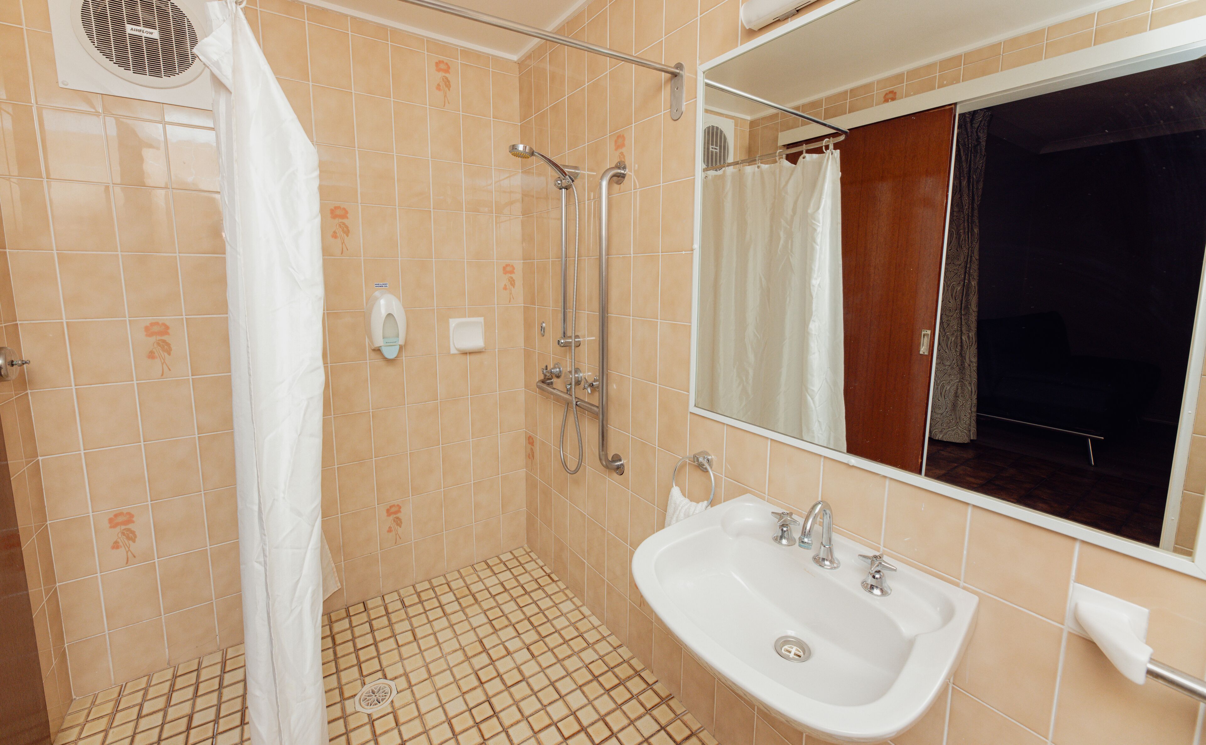 A bathroom with a shower, sink, and mirror.