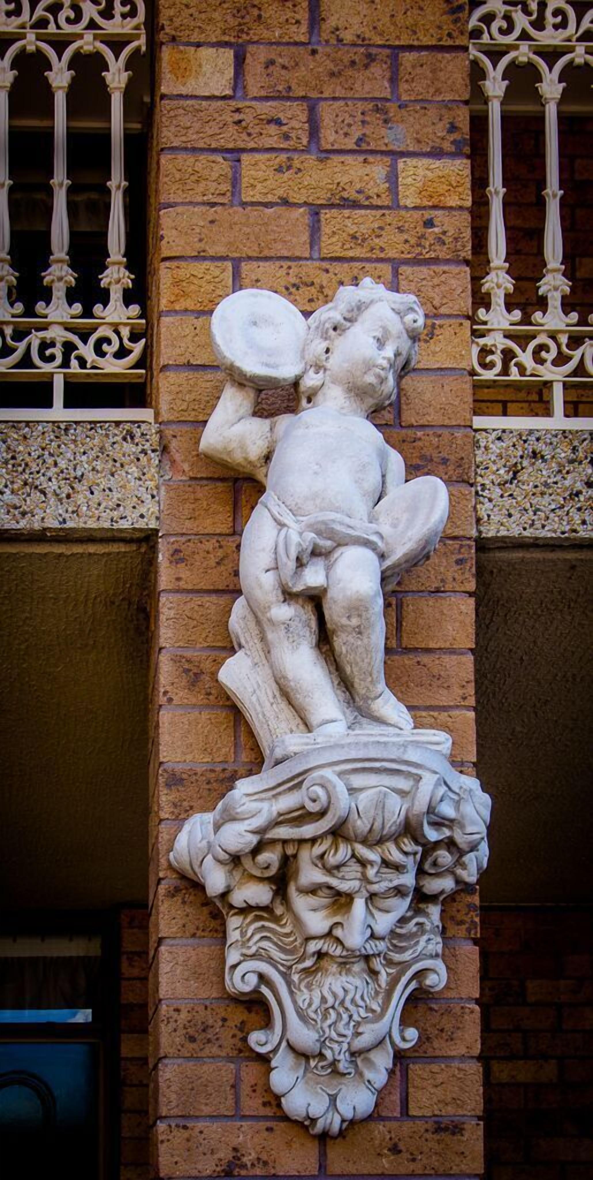 A stone relief sculpture of a cherub on a brick wall.