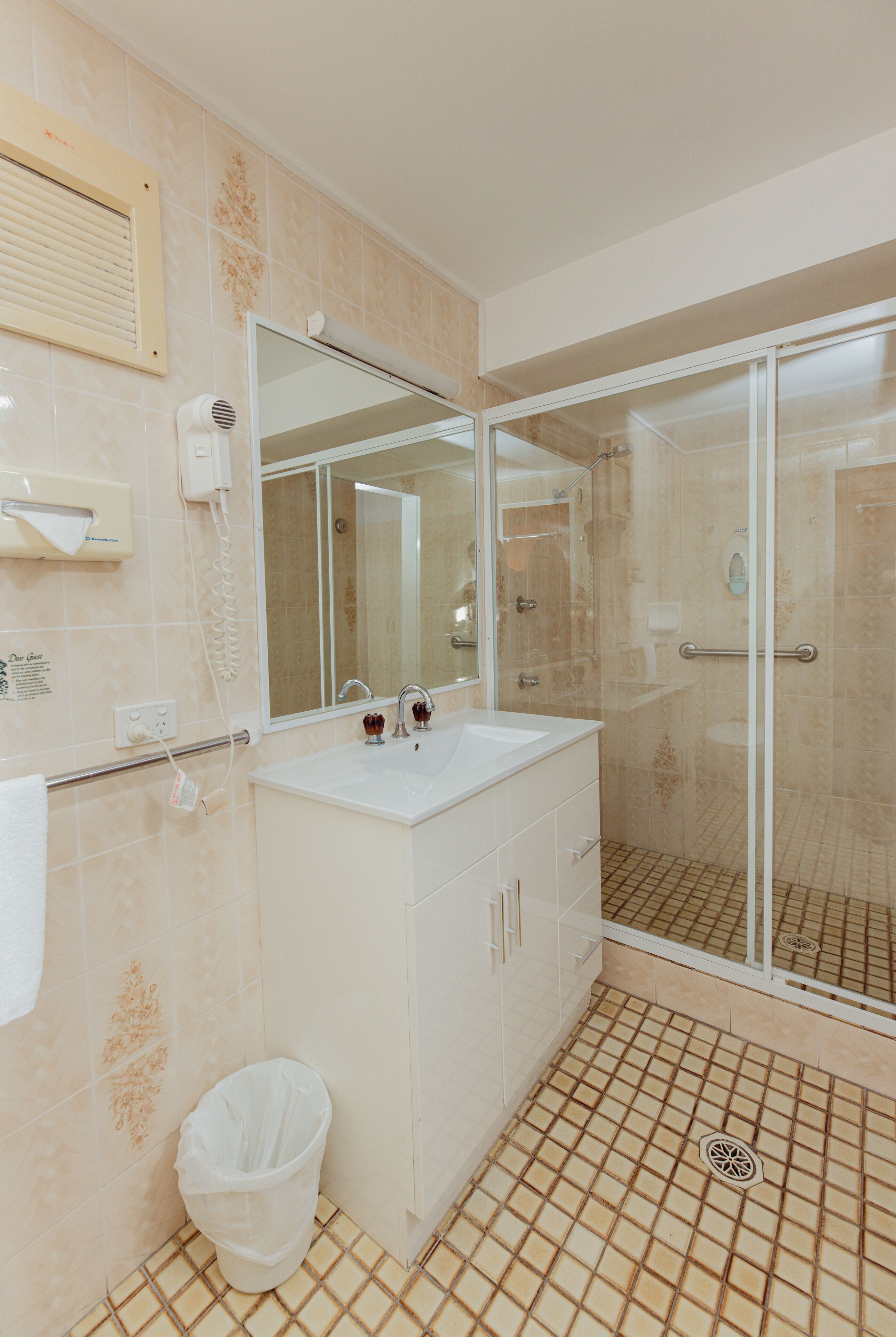 Un baño con ducha, lavamanos y espejo.