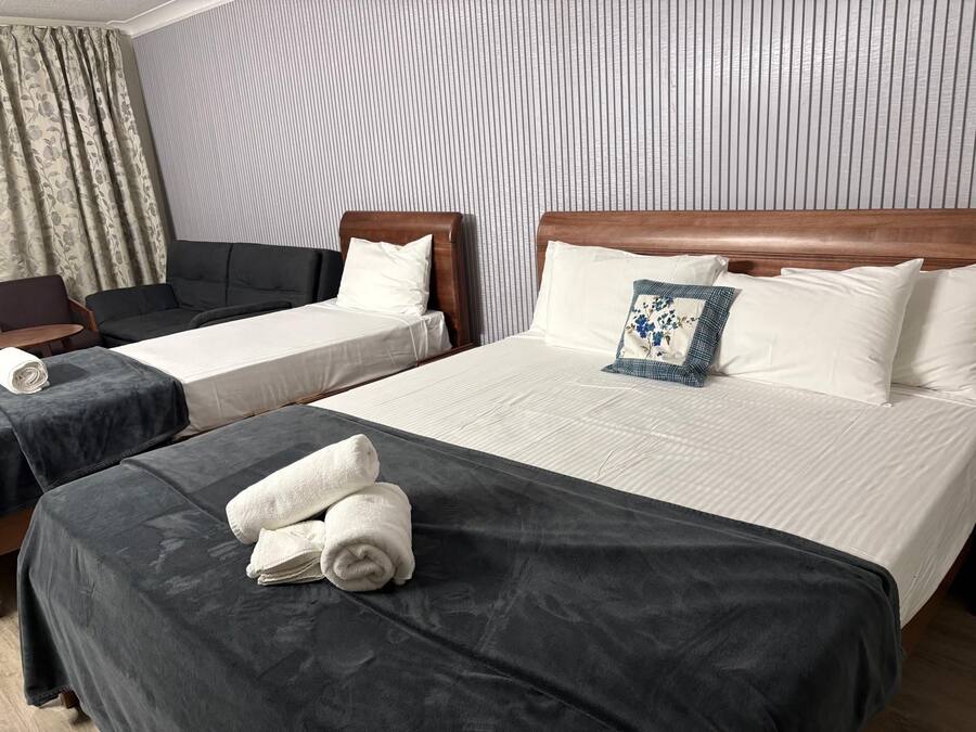 A hotel room with two single beds, a sofa, and a chair.