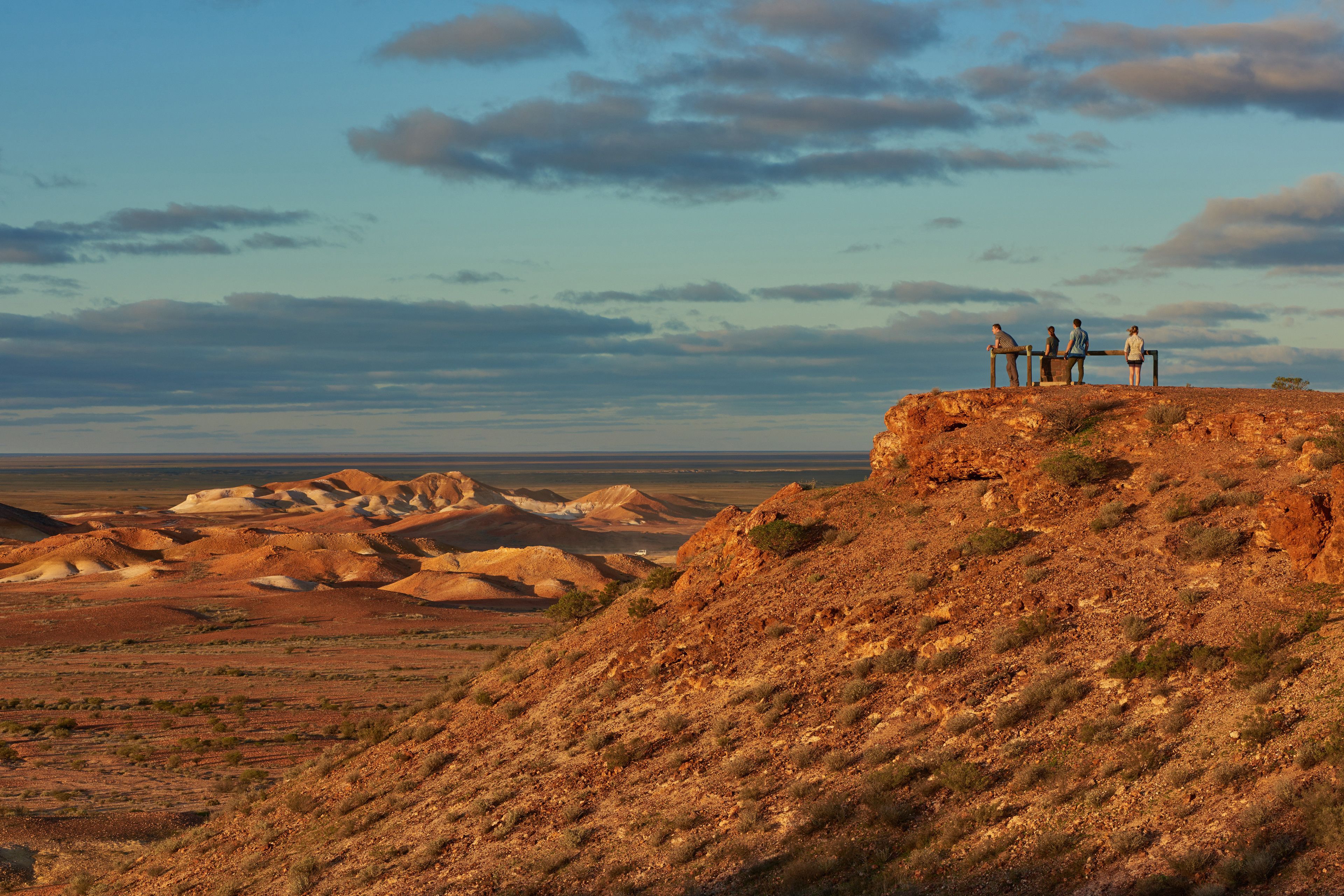 A desert landscape with a group of people standing on a rocky outcrop.