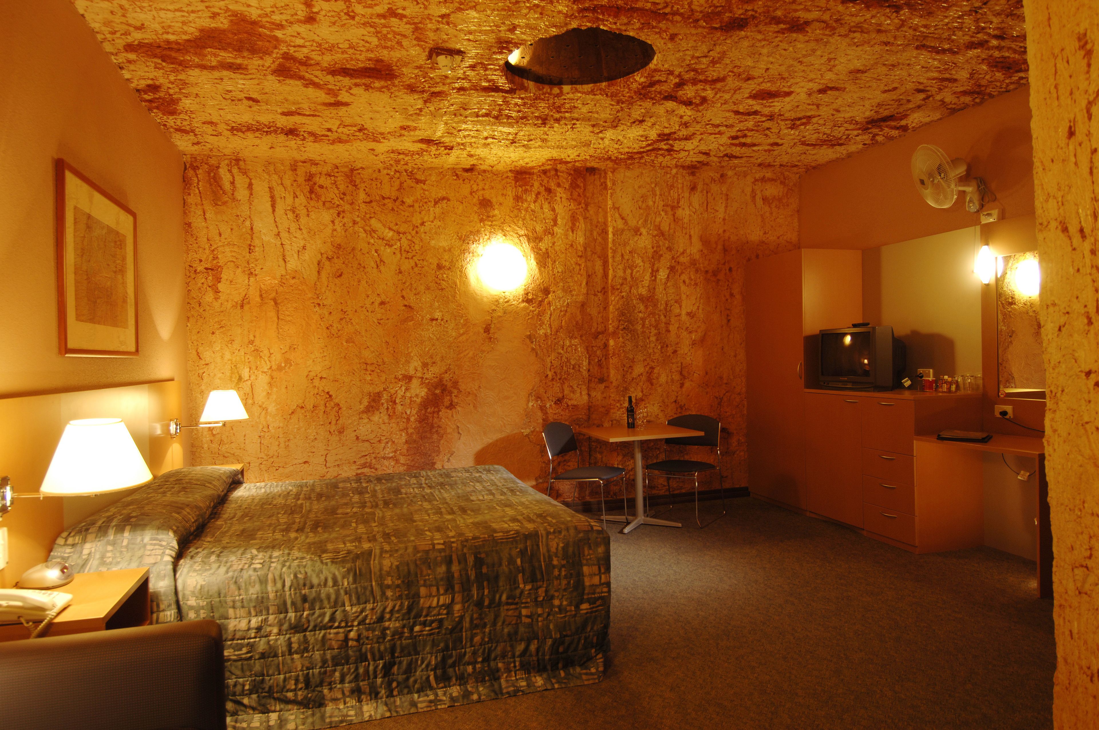 Ein Hotelzimmer mit Bett, Schreibtisch, Stuhl, kleinem Tisch, Spiegel und Fernseher.