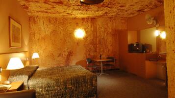Ein Hotelzimmer mit Bett, Schreibtisch, Stuhl, kleinem Tisch, Spiegel und Fernseher.