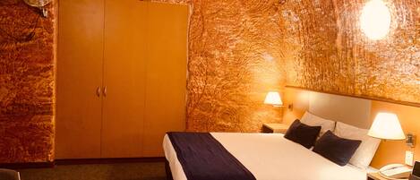 A hotel room with a bed, bedside lamps, a telephone, and a wardrobe.