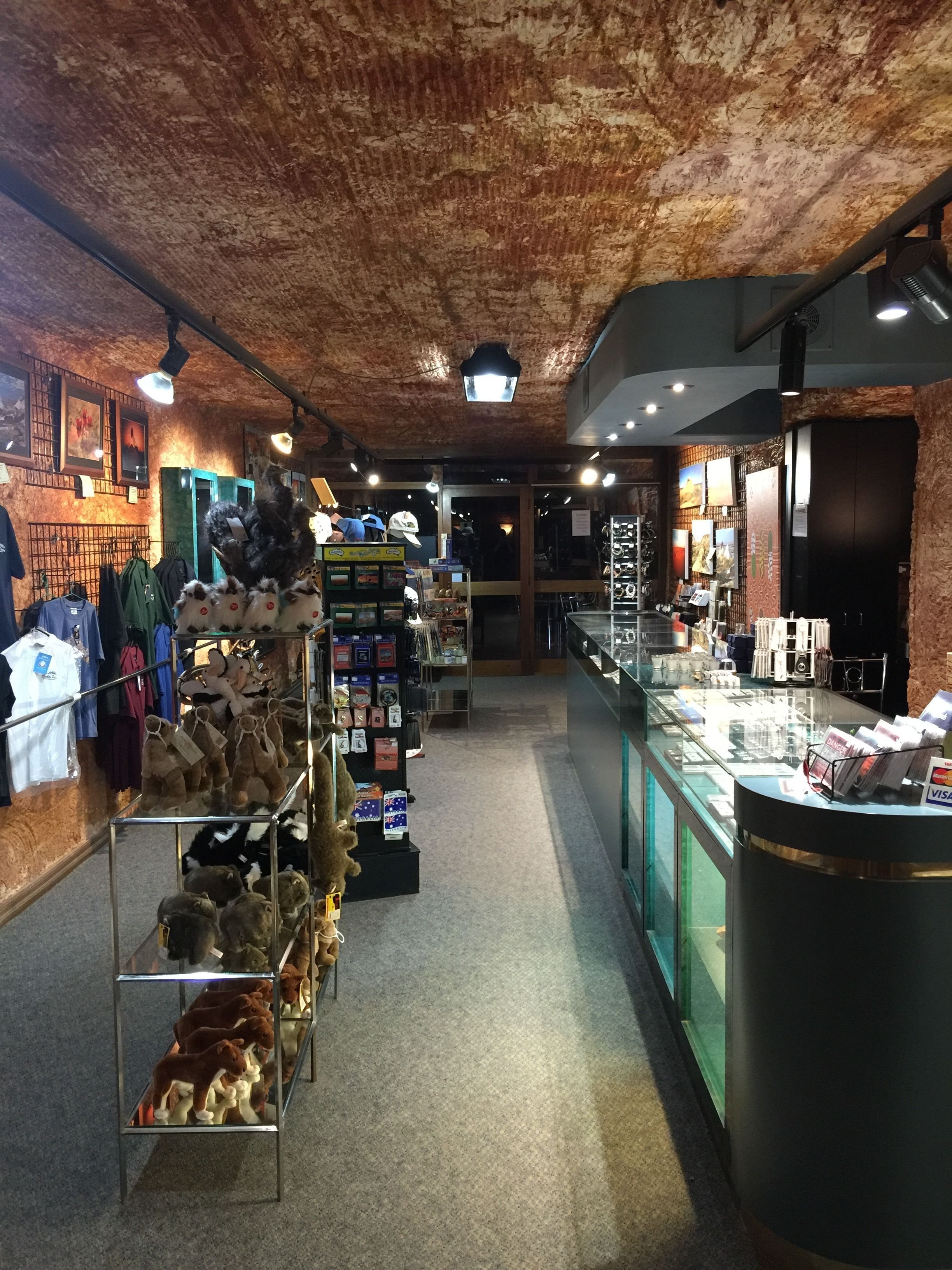 Een winkel met een rustiek plafond, glazen vitrines en diverse artikelen op planken.