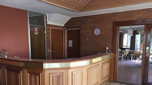 A reception desk with a clock, a fire exit sign, and a no smoking sign.