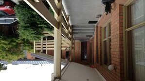 A covered outdoor area with a brick wall, a window, and a door.