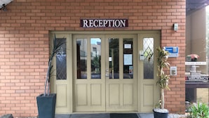 A reception area with a sign above the door, a security keypad, and a parking meter.