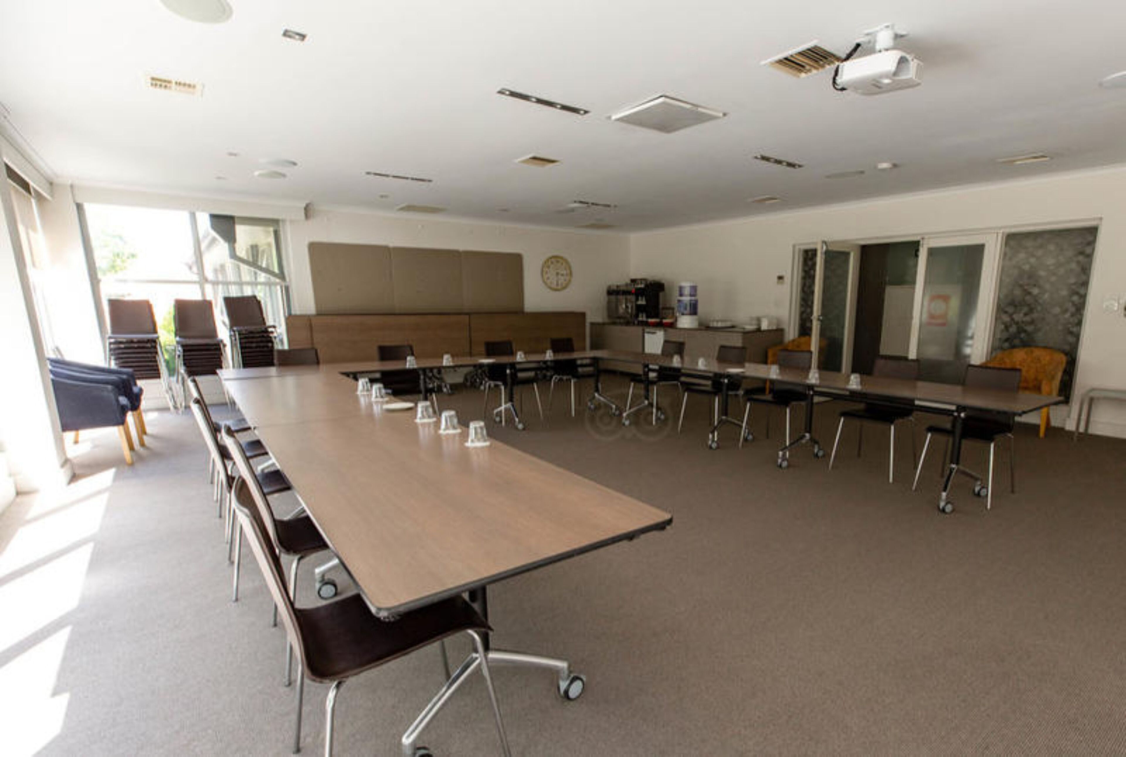Un salón de conferencias con una larga mesa, sillas y un proyector.