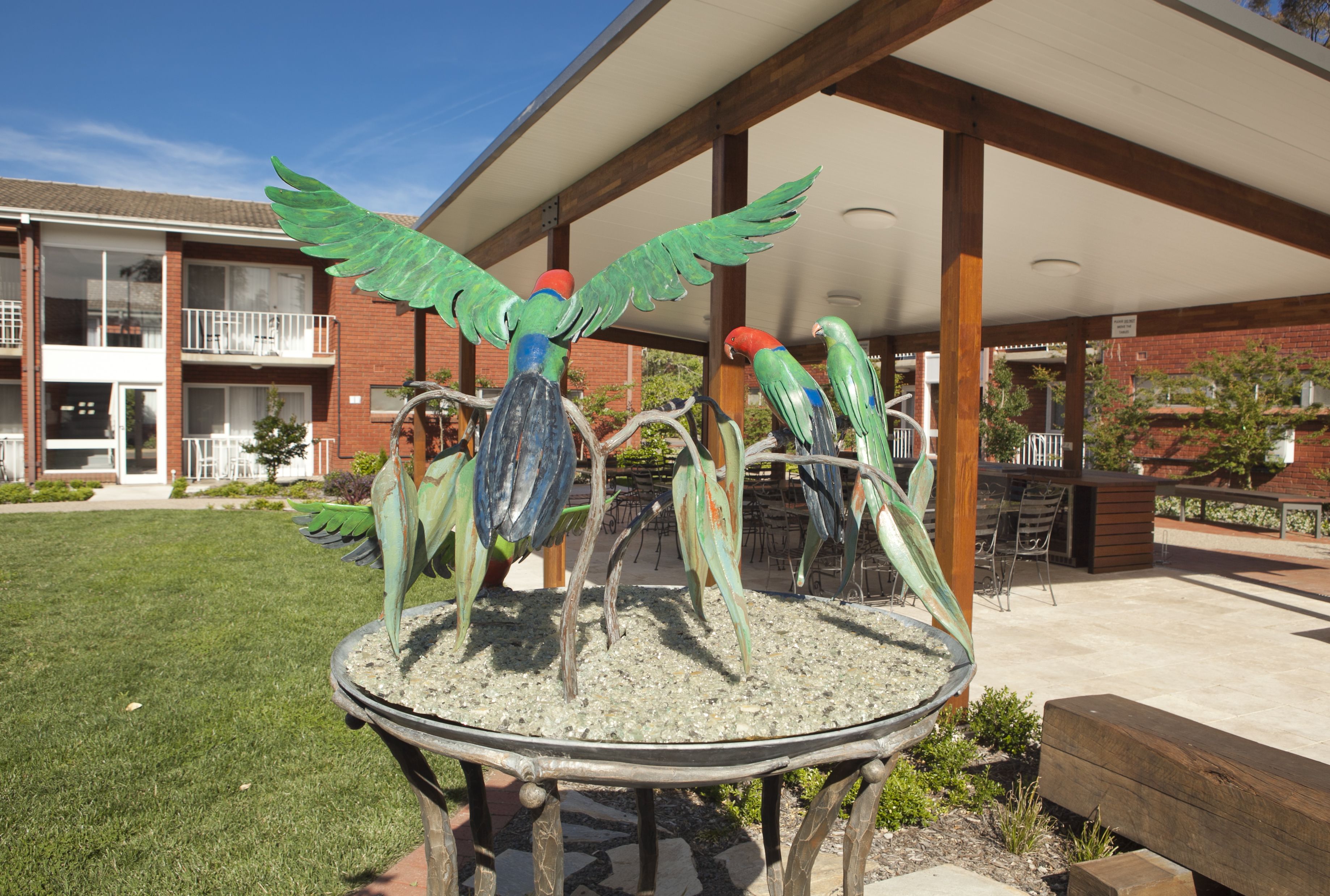 A building with a covered patio area, outdoor seating, and a decorative bird sculpture.