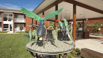 A building with a covered patio area, outdoor seating, and a decorative bird sculpture.