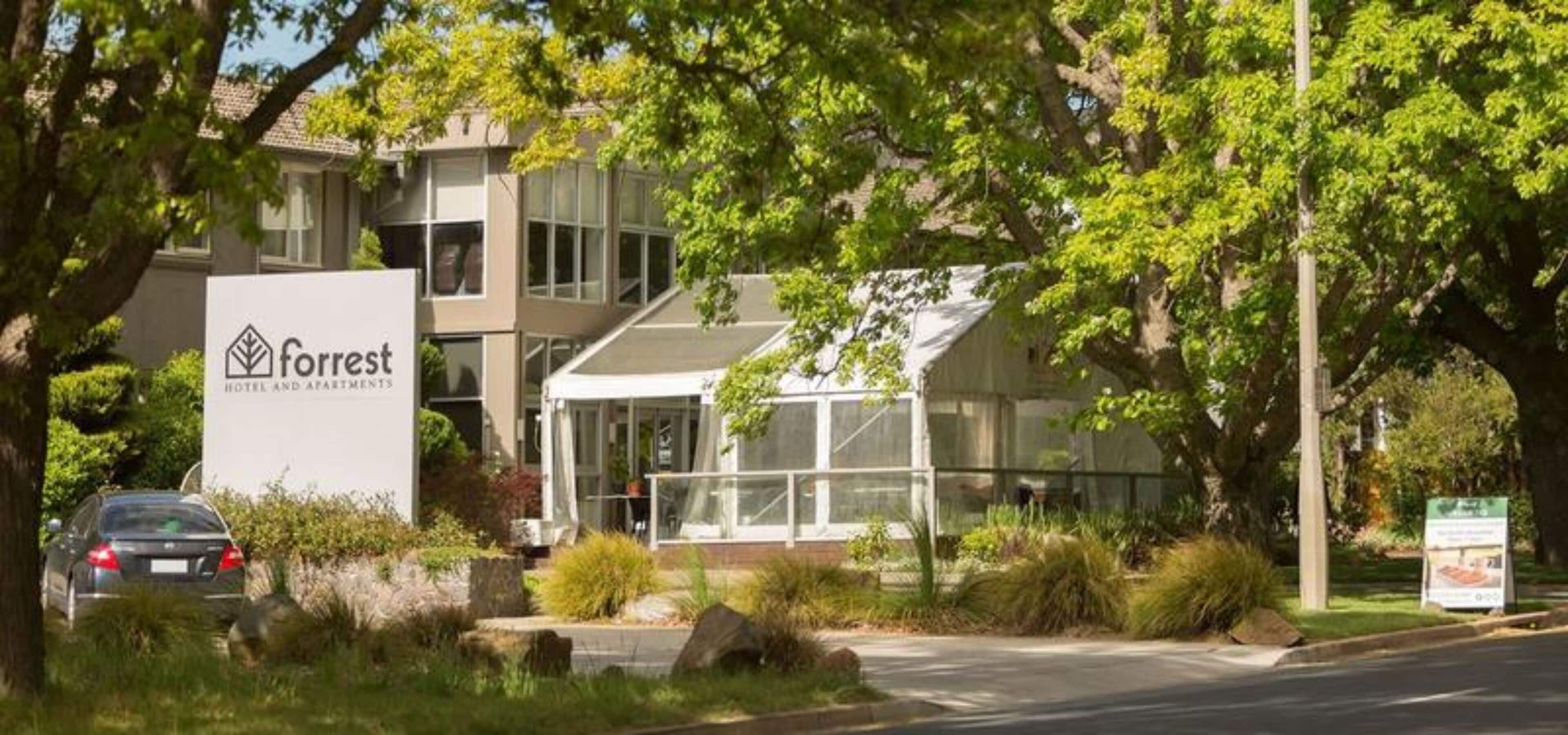 Een modern hotel met een bord waarop staat: Forrest Hotel and Apartments.